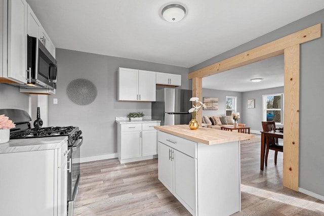 kitchen with white cabinetry, light hardwood / wood-style flooring, stainless steel appliances, and a center island