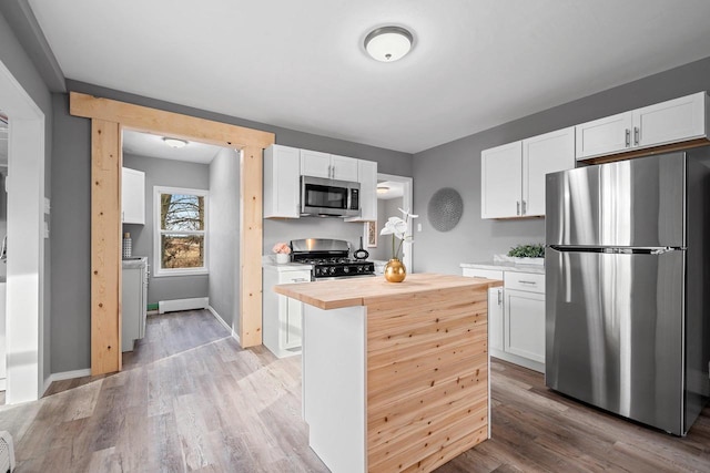 kitchen with stainless steel appliances, white cabinetry, and wooden counters