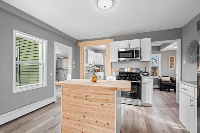 kitchen featuring white cabinetry, a baseboard heating unit, light wood-type flooring, and appliances with stainless steel finishes