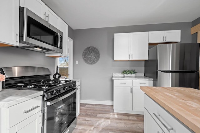 kitchen with stainless steel appliances, light hardwood / wood-style floors, and white cabinets