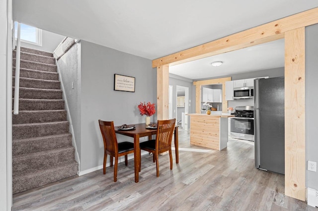 dining area featuring beam ceiling and light wood-type flooring