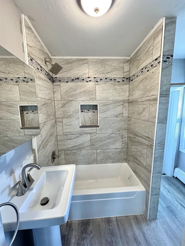 bathroom with hardwood / wood-style floors, tiled shower / bath combo, and sink