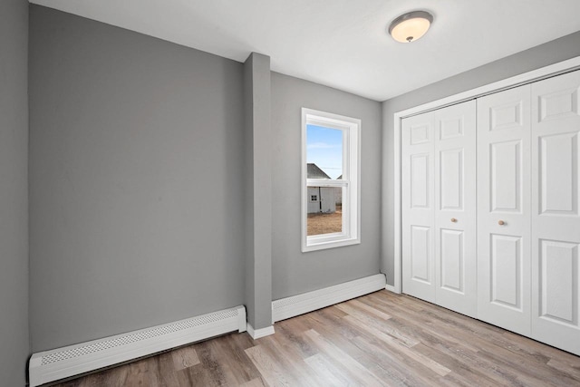 unfurnished bedroom with a baseboard radiator, a closet, and light hardwood / wood-style flooring