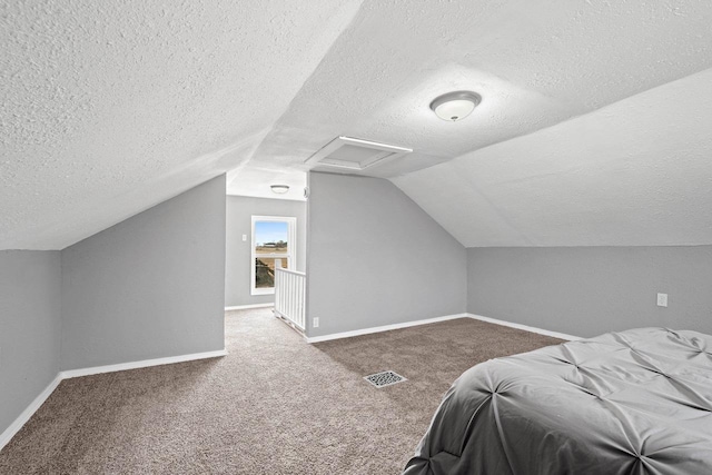 bedroom featuring lofted ceiling, carpet flooring, and a textured ceiling