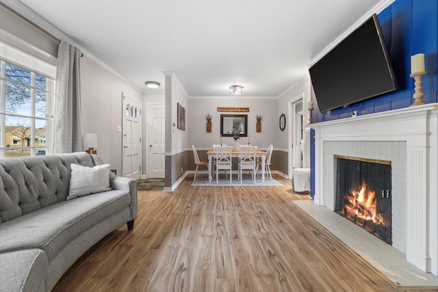 living room featuring a brick fireplace, crown molding, and wood-type flooring