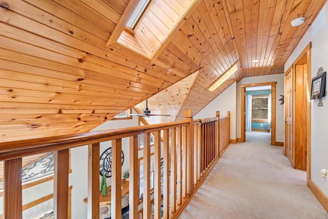 hall featuring lofted ceiling with skylight, light colored carpet, and wooden ceiling