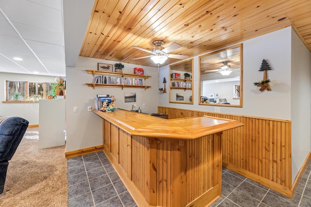 bar with ceiling fan, wooden walls, dark tile patterned flooring, and wooden ceiling