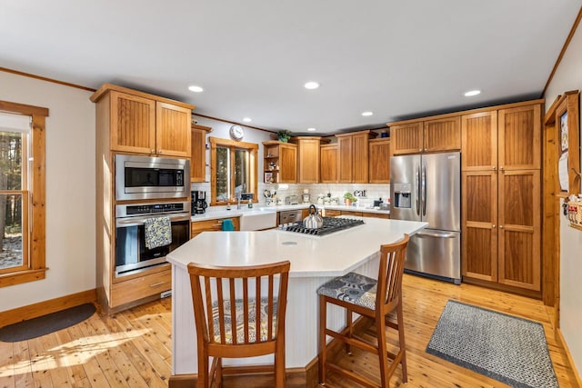 kitchen with backsplash, stainless steel appliances, light hardwood / wood-style floors, and a kitchen island