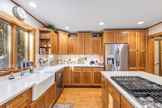 kitchen with appliances with stainless steel finishes, sink, decorative backsplash, ornamental molding, and light wood-type flooring