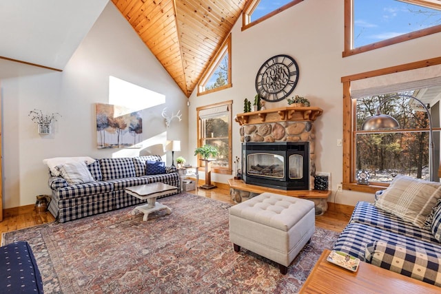 living room featuring hardwood / wood-style flooring, a wealth of natural light, high vaulted ceiling, and a stone fireplace