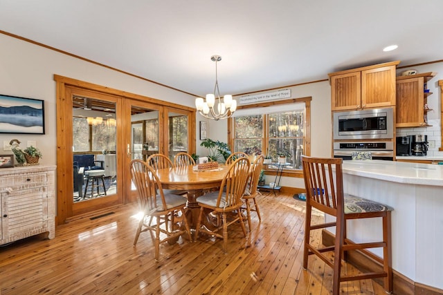 dining room featuring ornamental molding, a chandelier, and light wood-type flooring