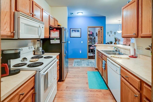 kitchen featuring sink, white appliances, and light wood-type flooring