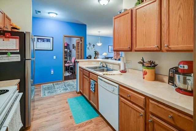 kitchen featuring hanging light fixtures, sink, white appliances, and light hardwood / wood-style floors