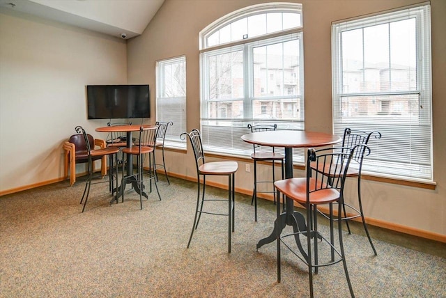 carpeted dining room with plenty of natural light and vaulted ceiling