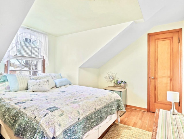 bedroom with lofted ceiling and light wood-type flooring