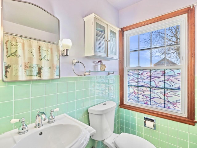 bathroom featuring sink, tile walls, and toilet