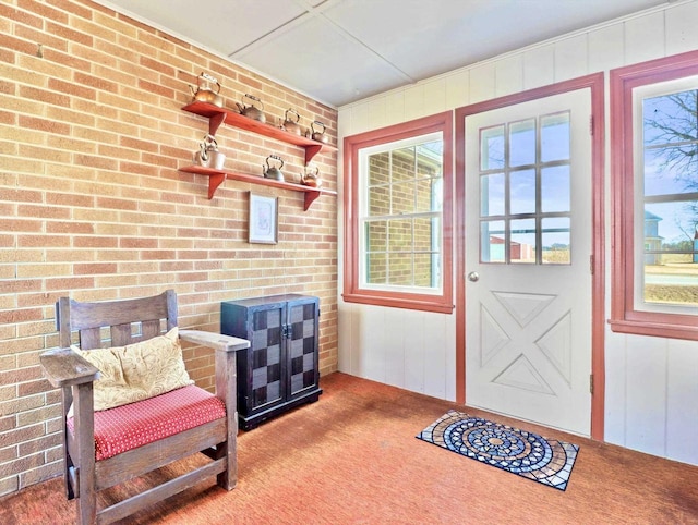 entryway with brick wall and carpet flooring