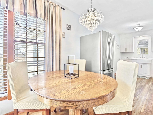 dining area with an inviting chandelier, sink, a healthy amount of sunlight, and light wood-type flooring