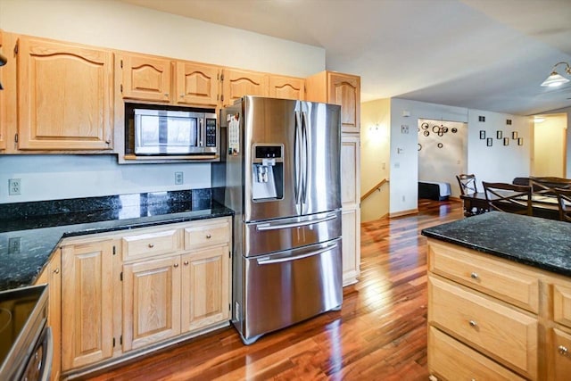 kitchen with appliances with stainless steel finishes, dark hardwood / wood-style floors, light brown cabinetry, and dark stone counters