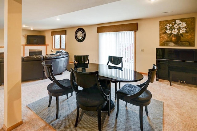 dining space featuring a tiled fireplace and carpet flooring