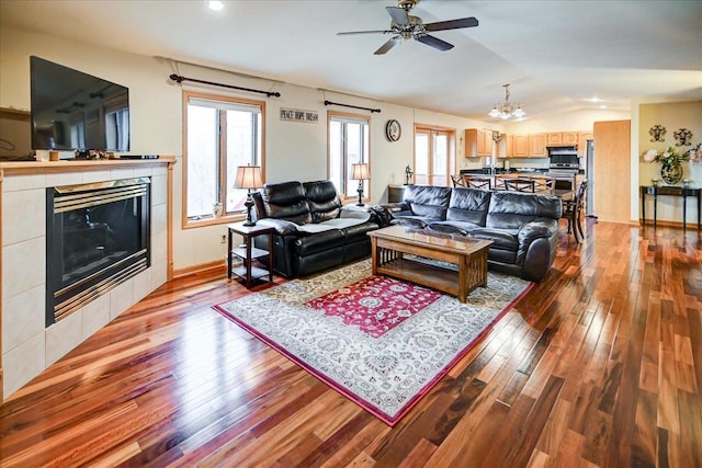 living room with lofted ceiling, ceiling fan with notable chandelier, a fireplace, and light hardwood / wood-style floors