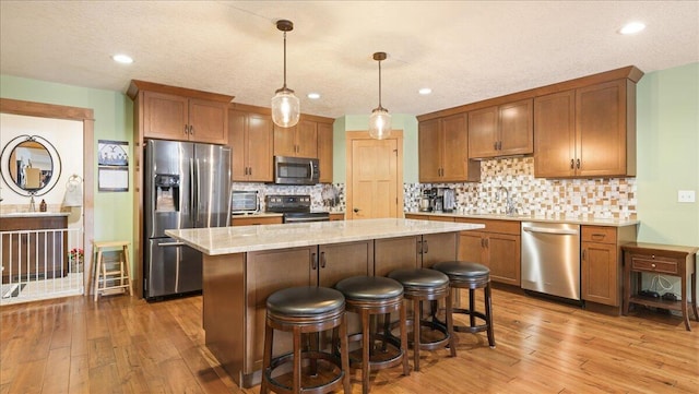 kitchen featuring pendant lighting, light hardwood / wood-style flooring, a center island, and appliances with stainless steel finishes