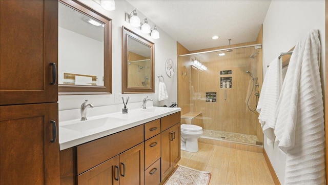 bathroom featuring vanity, a textured ceiling, a shower with shower door, and toilet