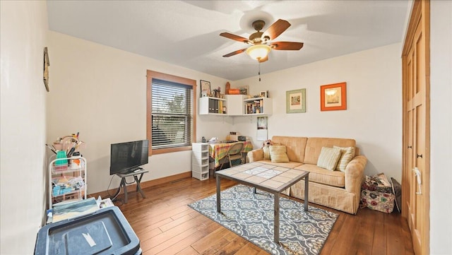 living room featuring dark wood-type flooring and ceiling fan