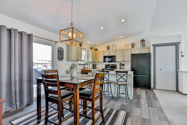 dining room featuring lofted ceiling, sink, and wood-type flooring