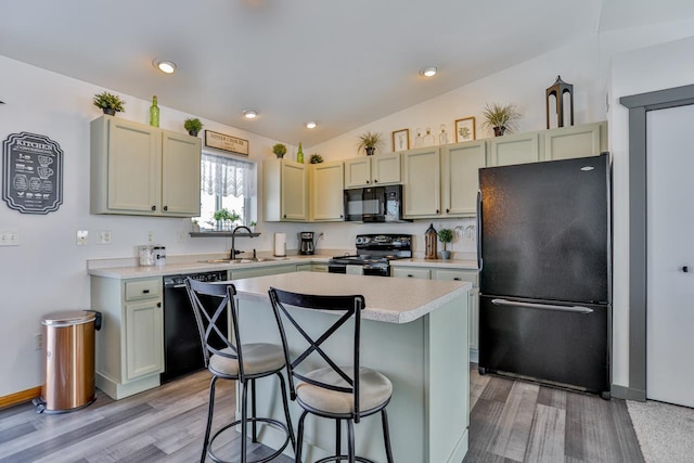 kitchen with lofted ceiling, sink, a breakfast bar, black appliances, and a kitchen island