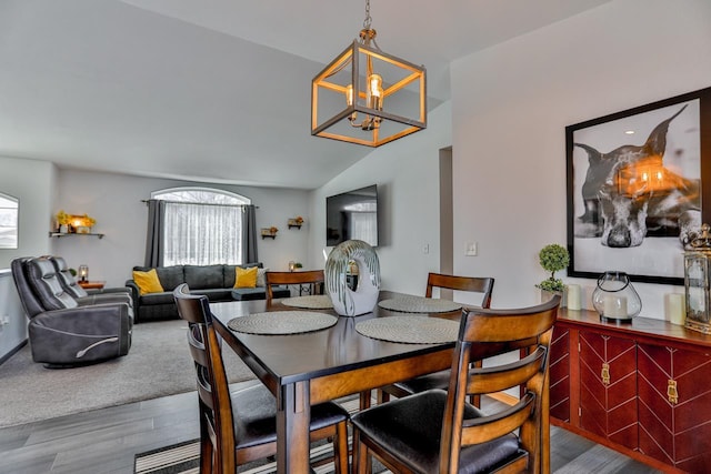 dining room featuring an inviting chandelier, hardwood / wood-style flooring, vaulted ceiling, and a wealth of natural light