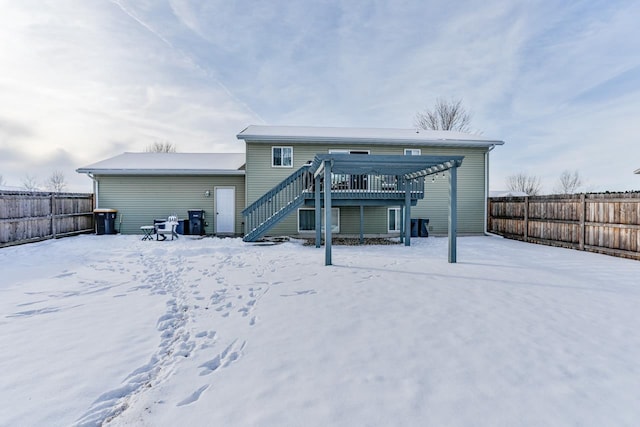 snow covered rear of property with a deck