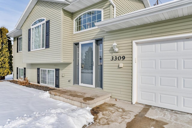 snow covered property entrance featuring a garage