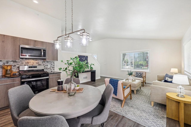 dining area featuring vaulted ceiling and dark wood-type flooring