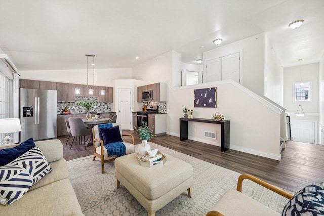 living room featuring dark wood-type flooring and vaulted ceiling