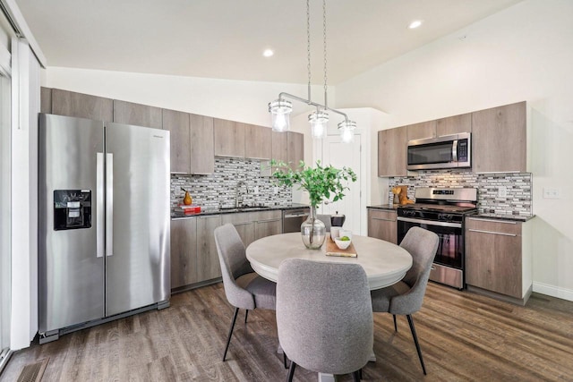 kitchen featuring pendant lighting, appliances with stainless steel finishes, dark wood-type flooring, and sink