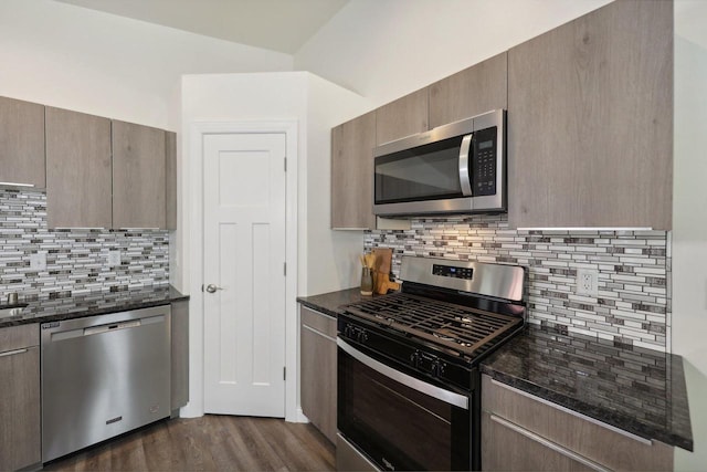 kitchen featuring dark stone countertops, decorative backsplash, dark hardwood / wood-style flooring, and appliances with stainless steel finishes