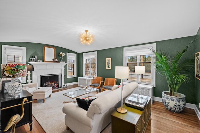 living room with vaulted ceiling, a fireplace, and light wood-type flooring