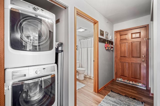 clothes washing area featuring stacked washer and clothes dryer and light hardwood / wood-style flooring