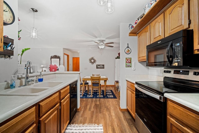 kitchen featuring wood-type flooring, sink, hanging light fixtures, ceiling fan, and black appliances