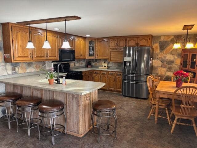 kitchen featuring decorative light fixtures, black appliances, a chandelier, a kitchen breakfast bar, and kitchen peninsula