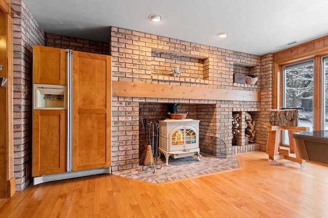 2532 Huntington Way, Suamico, WI 54173 - unfurnished living room featuring a wood stove, hardwood / wood-style flooring, brick wall, and visible vents