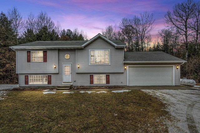 bi-level home with a garage and a lawn