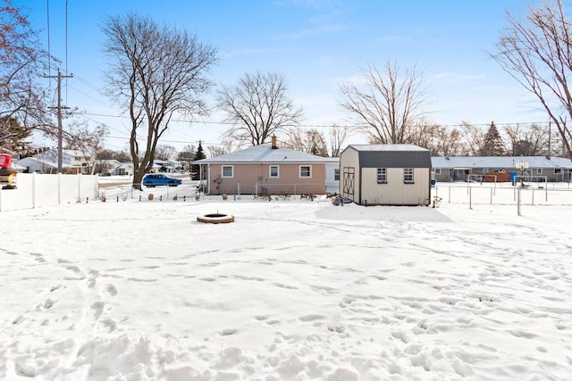 snow covered rear of property with a storage unit