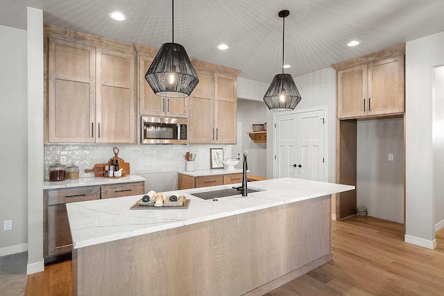 kitchen with pendant lighting, light stone countertops, sink, and decorative backsplash