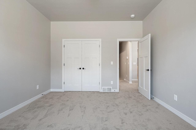 unfurnished bedroom featuring light carpet and a closet