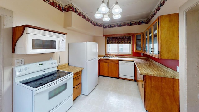 kitchen featuring white appliances, decorative light fixtures, a chandelier, and sink