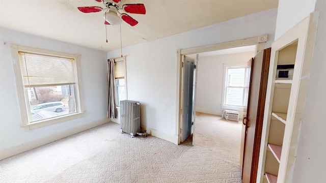 carpeted empty room featuring ceiling fan, radiator heating unit, and a healthy amount of sunlight