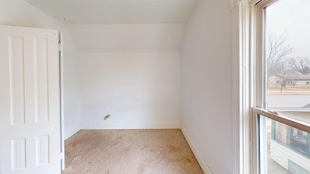 spare room featuring light colored carpet and vaulted ceiling