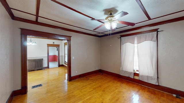 empty room featuring ornamental molding, radiator, hardwood / wood-style floors, and ceiling fan